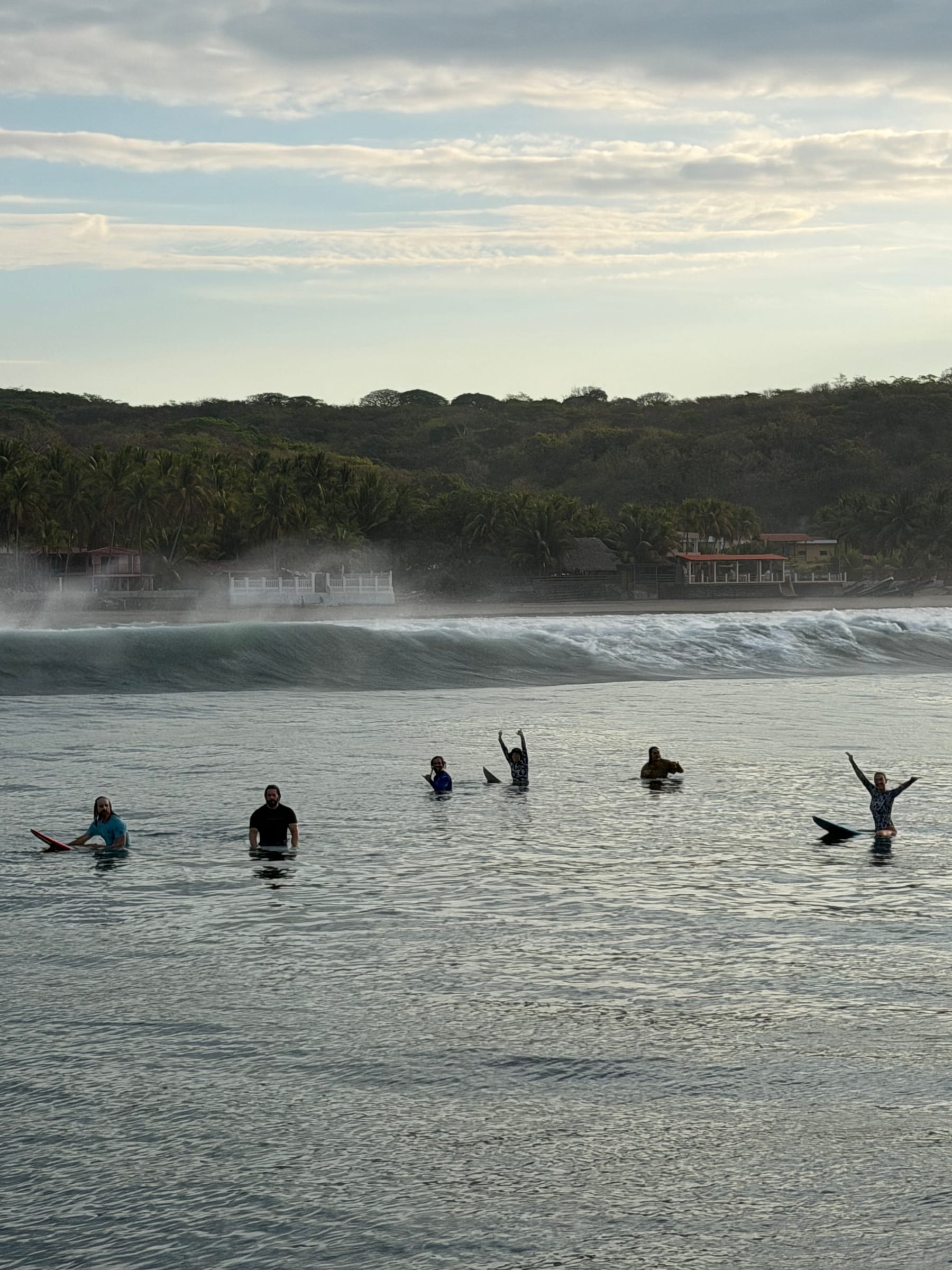 Surfers watching the waves from the water at sunset in El Salvador