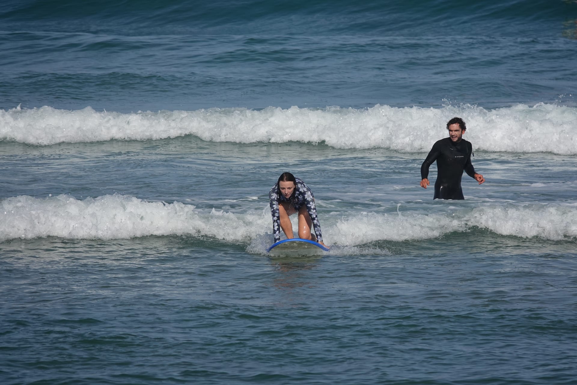 Surf student paddling through whitewater with a coach nearby