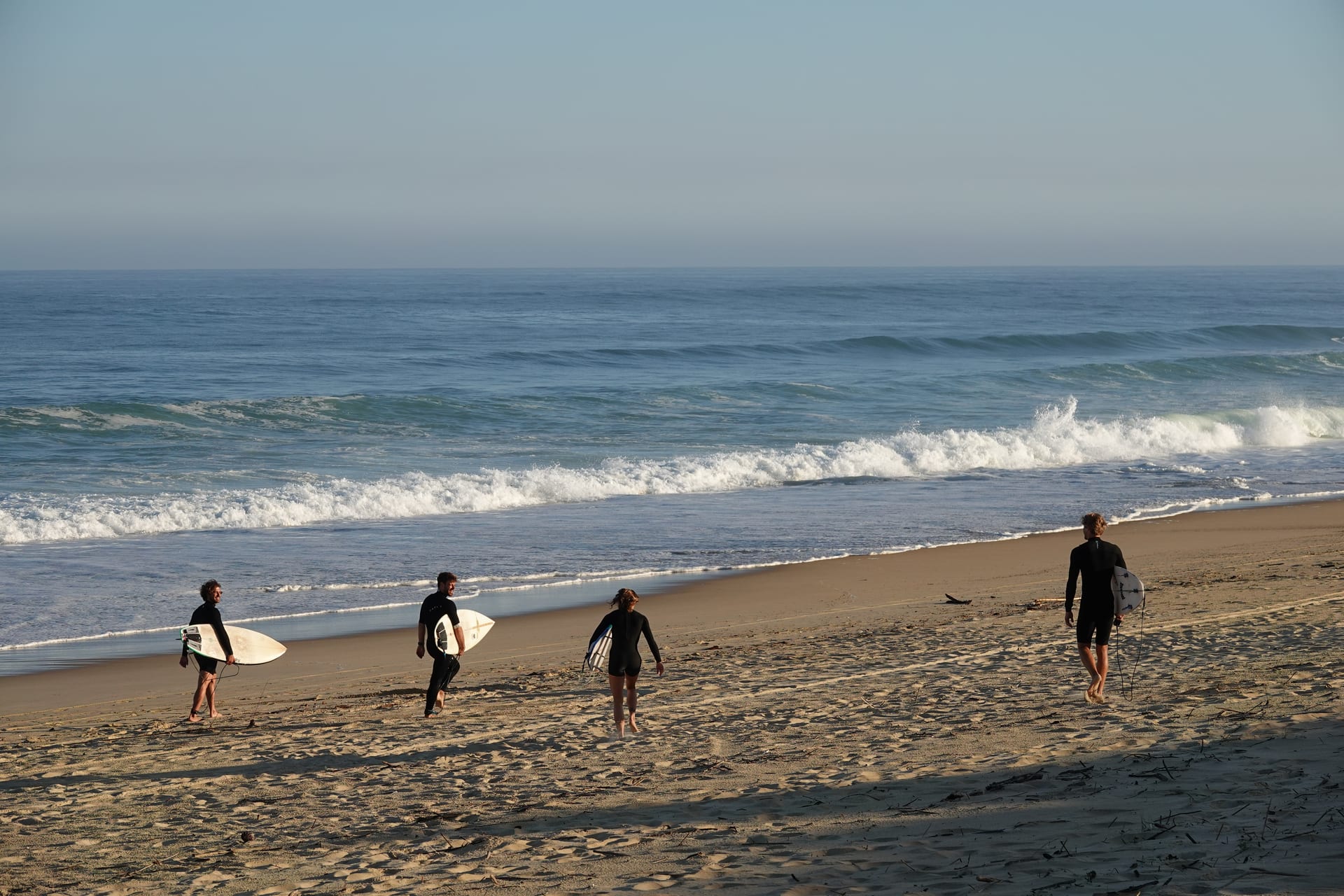 Surfers walking toward powerful beach break waves in France
