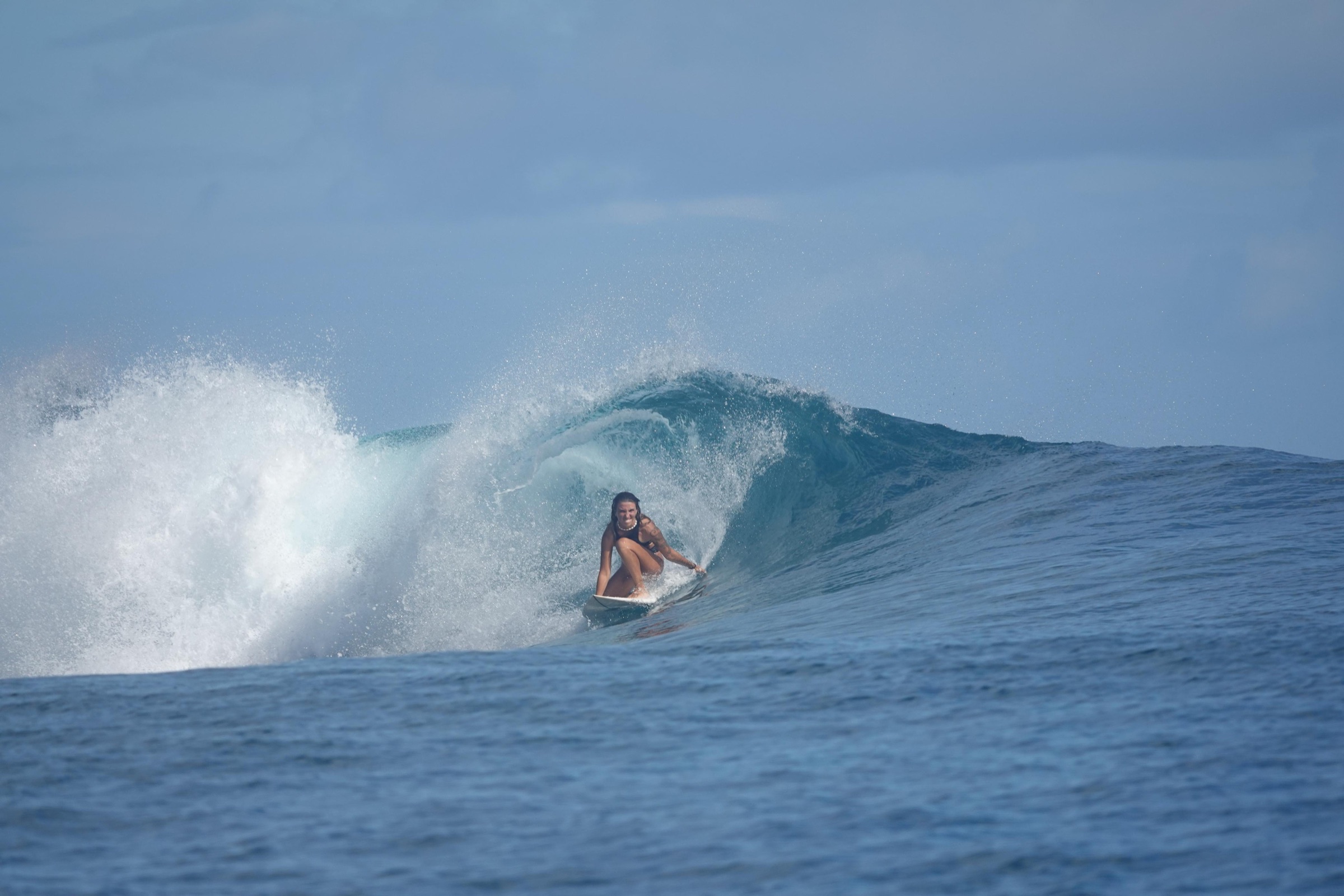 Surfer carving across a blue Mentawai wave