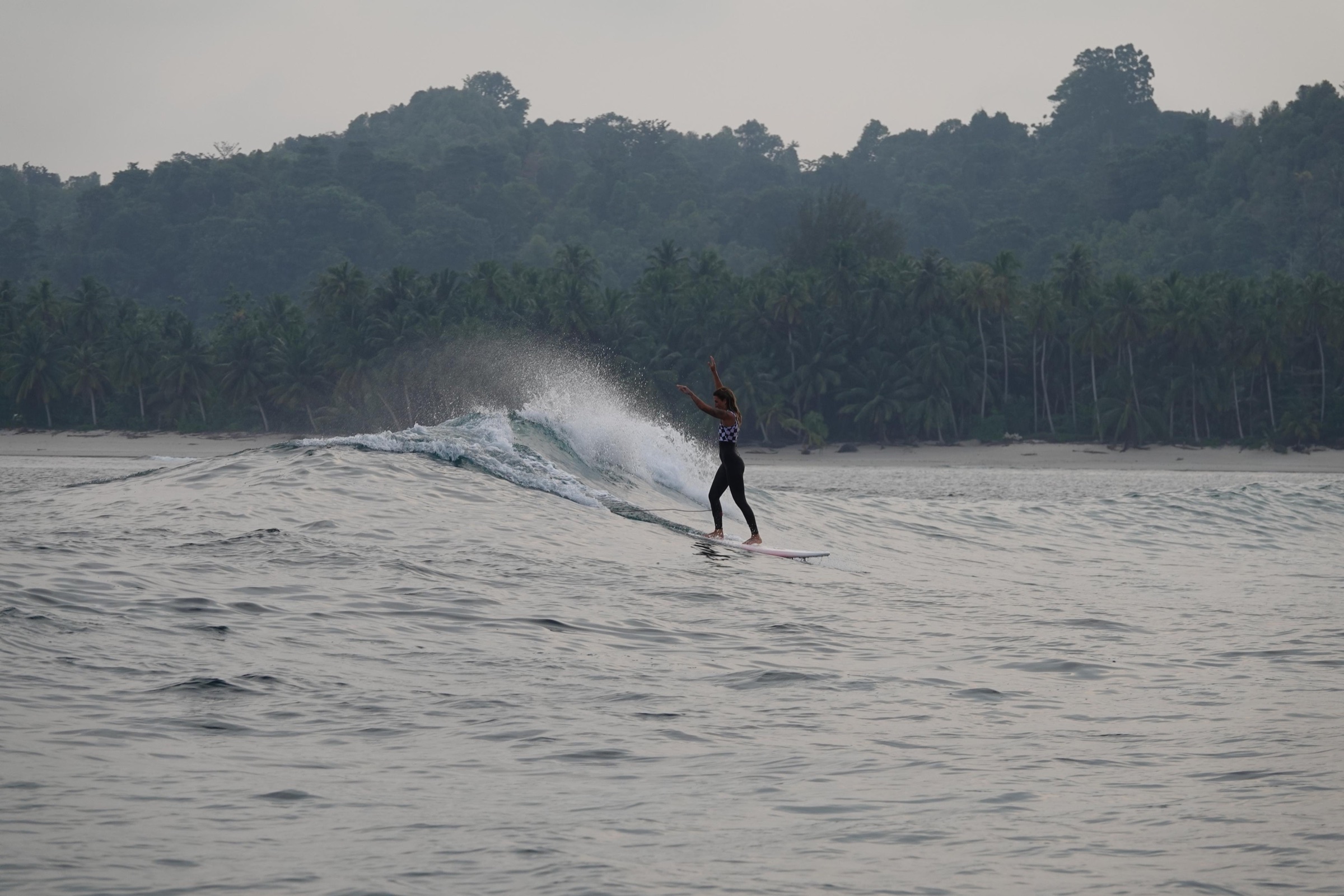Longboard surfer gliding near a tropical Mentawai island